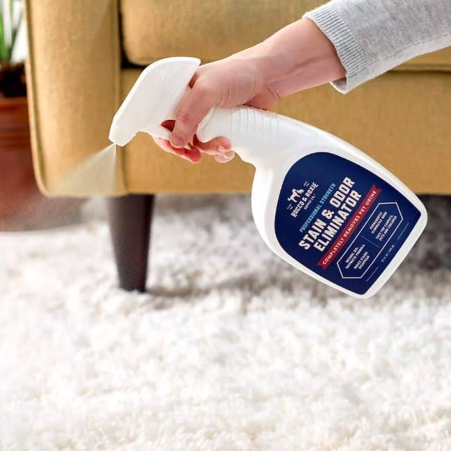 Person using the spray on a fluffy white rug