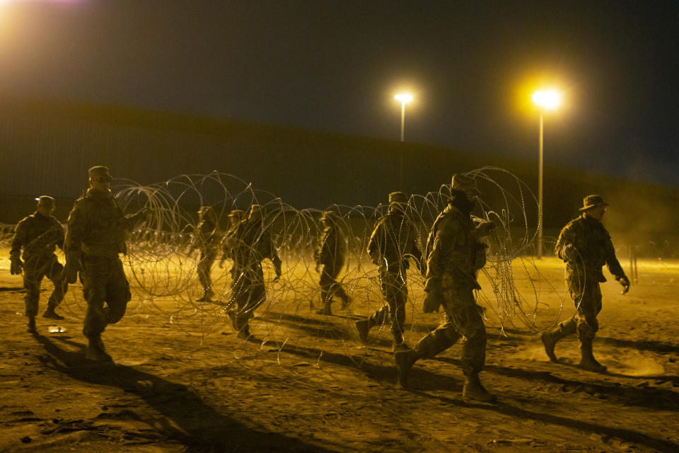 Texas National Guard soldiers carry a barbed-wire to be installed near a gate at the border fence in El Paso, Texas, in the early hours of Thursday, May 11, 2023. Migrants rushed across the border hours before pandemic-related asylum restrictions were to expire Thursday, fearing that new policies would make it far more difficult to gain entry into the United States. (AP Photo/Andres Leighton)