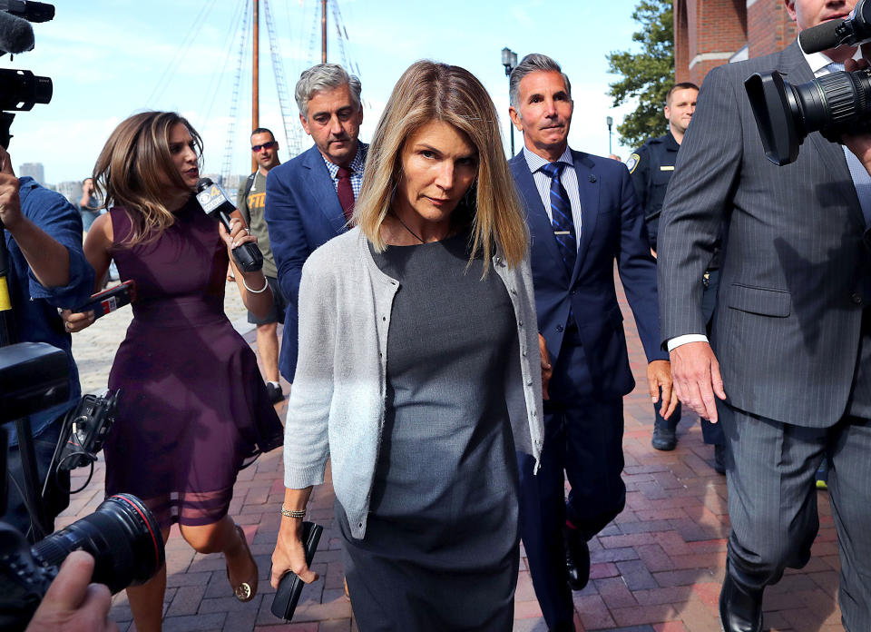 BOSTON, MA - AUGUST 27: Lori Loughlin, center, and her husband Mossimo Giannulli, behind her at right, leave the John Joseph Moakley United States Courthouse in Boston on Aug. 27, 2019. A judge says actress Lori Loughlin and her fashion designer husband, Mossimo Giannulli, can continue using a law firm that recently represented the University of Southern California. The couple appeared in Boston federal court on Tuesday to settle a dispute over their choice of lawyers in a sweeping college admissions bribery case. Prosecutors had said their lawyers pose a potential conflict of interest. Loughlin and Giannulli say the firms work for USC was unrelated to the admissions case and was handled by different lawyers. (Photo by John Tlumacki/The Boston Globe via Getty Images)