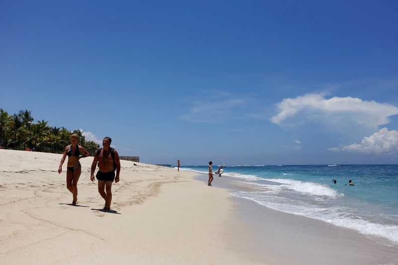 FILE PHOTO: Tourists walk along a beach in the luxury resort area of Nusa Dua
