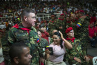 In this Feb. 6, 2019 photo, the wife of a soldier who was part of the group that attacked the presidential palace in a failed 1992 military coup organized by the late Hugo Chavez, checks her hair minutes before the start of the weekly, live TV program coined: "Con el Mazo Dando," or "Hitting it With a Sledgehammer," inside an aviation academy in Maracay, Venezuela. For government supporters attending the program, the enthusiasm for the show's host Diosdado Cabello, who the U.S. and European Union have sanctioned for human rights abuses and corruption, bordered on Elvis Presley-like idolatry. (AP Photo/Rodrigo Abd)