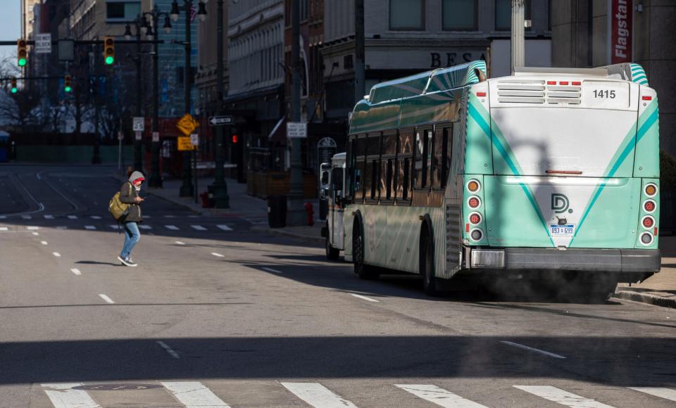 A person crosses the street to enter a SMART bus early morning outside the Coleman A. Young Municipal Center in Detroit on Feb. 14, 2023.