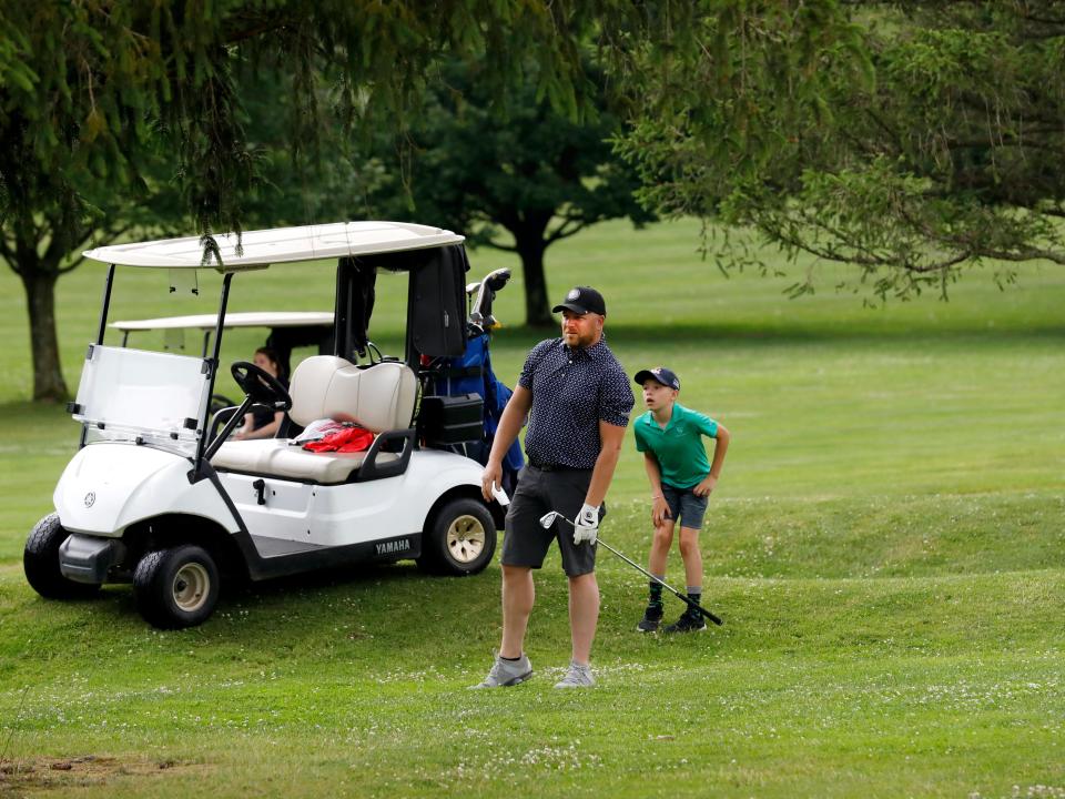 Brad Byers watches his approach shot on the 18th hole with his son keepoing a close eye during the first round of the 46th annual Zanesville District Golf Association Amateur tournament on Friday, June 24, 2023, at Hickory Flats Golf Course in West Lafayette, Ohio.