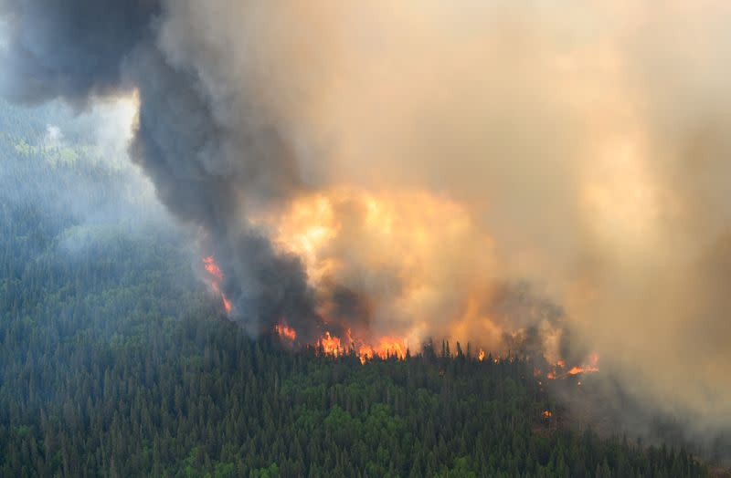 FILE PHOTO: Flames reach upwards along the edge of a wildfire as seen from a Canadian Forces helicopter in Quebec