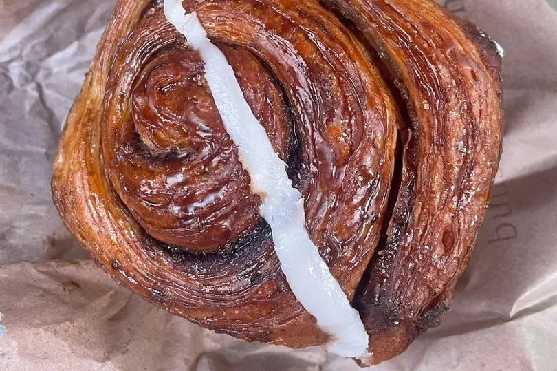 A freshly baked Buns From Home cinnamon bun out of the paper bag