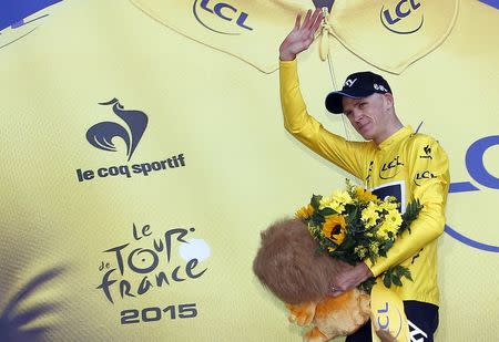 Team Sky rider Chris Froome of Britain waves as he wears the race leader's yellow jersey on the podium of the third stage of the 102nd Tour de France cycling race from Anvers to Huy, Belgium, July 6, 2015. REUTERS/Eric Gaillard