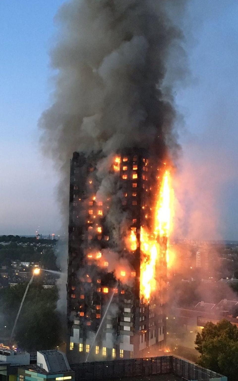 Thick smoke billows from Grenfell Tower as the fire rages in the early hours - Credit: NATALIE OXFORD/AFP