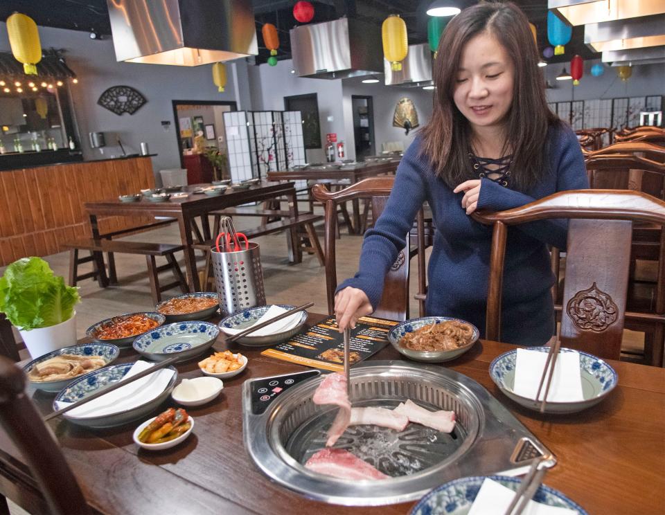 Skye Li demonstrates the Korean barbecye cooking technique at the new Lee's BBQ and Hot Pot restaurant on Tuesday.