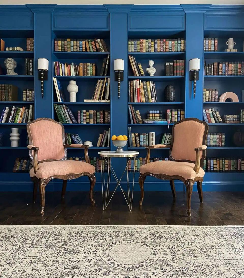 a couple chairs in front of a book shelf