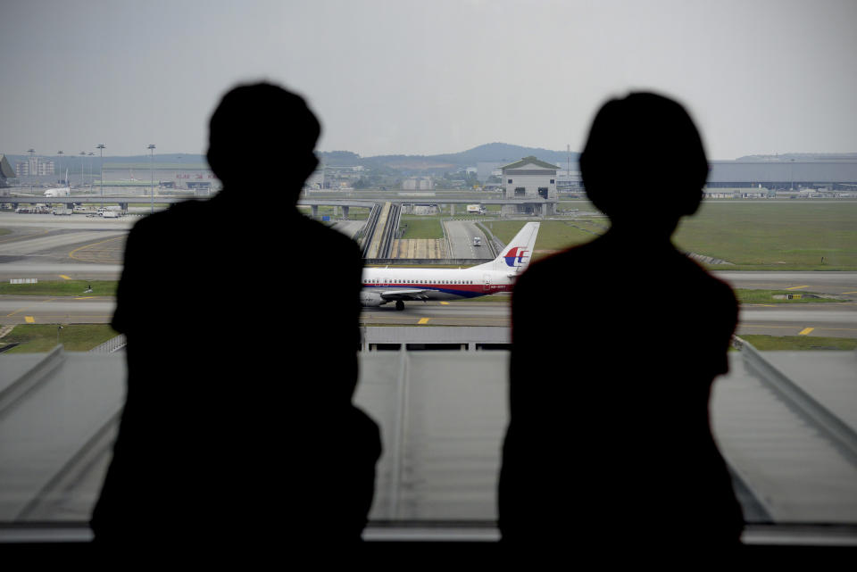 A couple is silhouetted as they watch a Malaysia Airlines plane on the tarmac from the viewing gallery at Kuala Lumpur International Airport in Sepang, Malaysia, Thursday, April 10, 2014. With hopes high that search crews are zeroing in on the missing Malaysian jetliner's crash site, ships and planes hunting for the aircraft intensified their search efforts on Thursday after equipment picked up sounds consistent with a plane's black box in the deep waters of the Indian Ocean. (AP Photo/Joshua Paul)