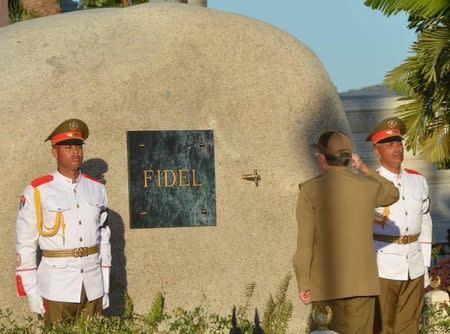 Cuba's President Raul Castro (C) salutes after placing the box containing the ashes of Cuba's former President Fidel Castro into a boulder at the Santa Ifigenia Cemetery, in Santiago de Cuba, December 4, 2016. REUTERS/ACN/Marcelino Vazquez/via REUTERS