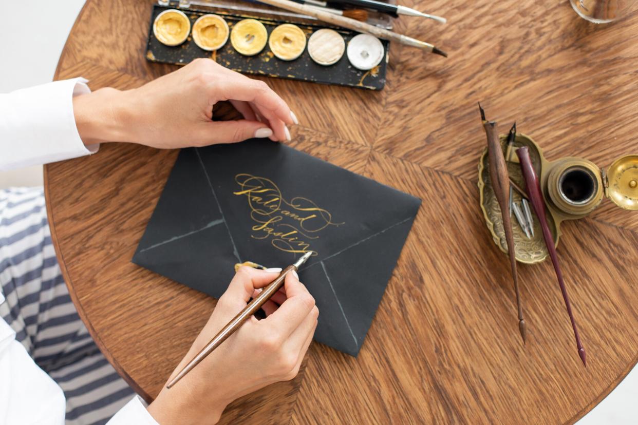 woman writing calligraphy on black envelope