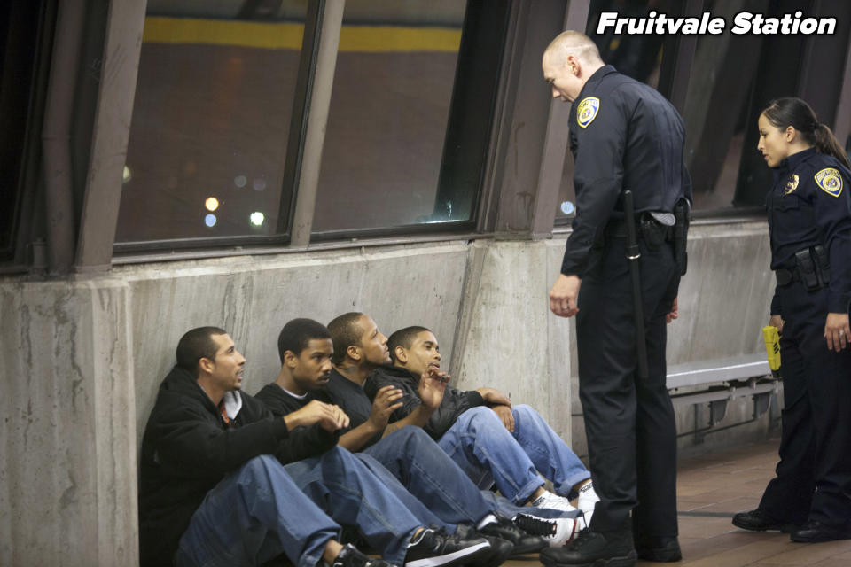 Two cops standing over four young men sitting on the ground from "Fruitvale Station"