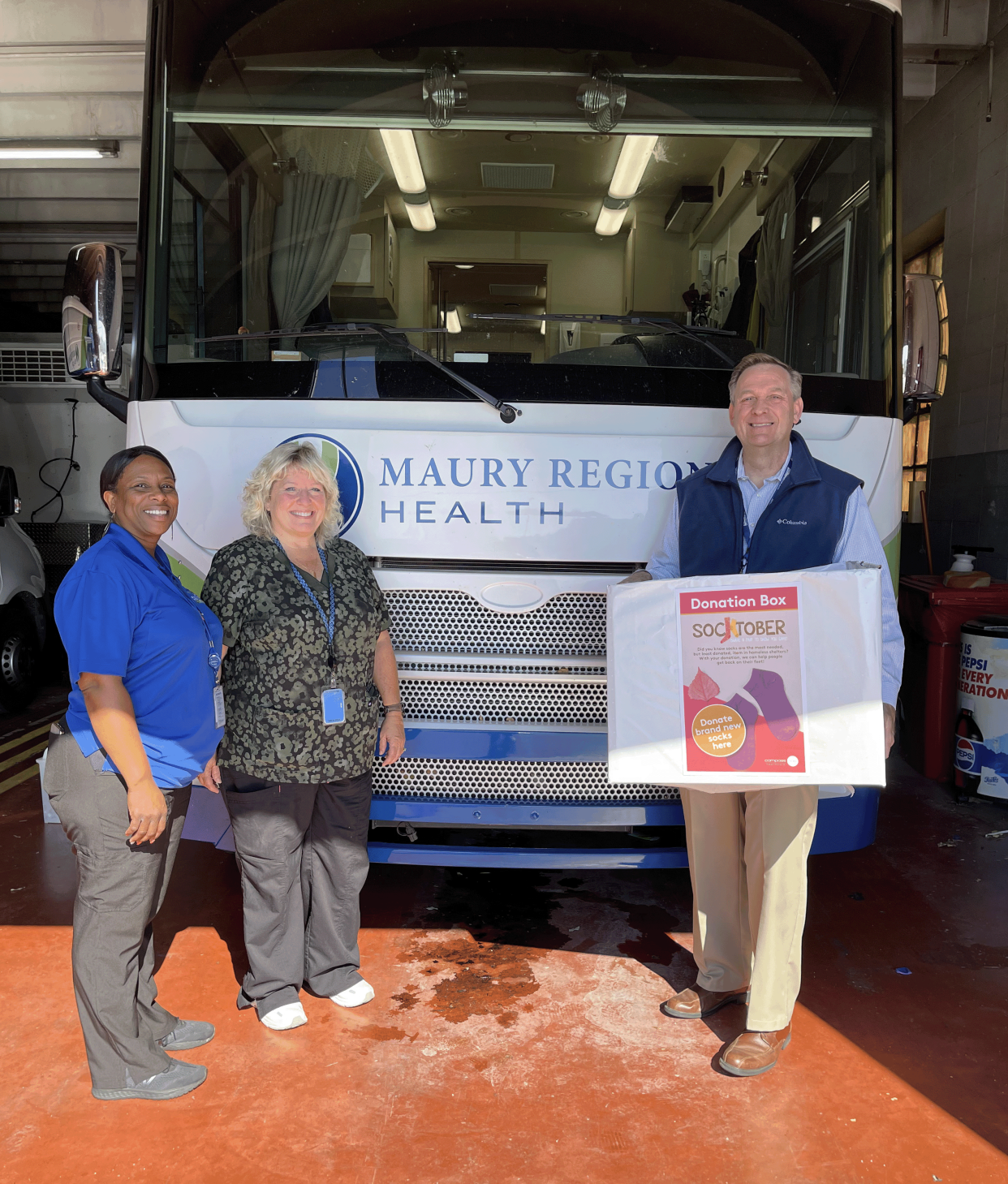 Cindy McCann (left), cafeteria supervisor for Maury Regional Health, delivers donated socks to Lori Bergland (middle), RN, the community health nurse for the Maury Regional Mobile Medical Clinic, and Patrick Harlan, director of business development for Maury Regional Health and the mobile unit operations manager. Maury Regional Health employees donated 397 pairs of socks during the Socktober campaign in October.