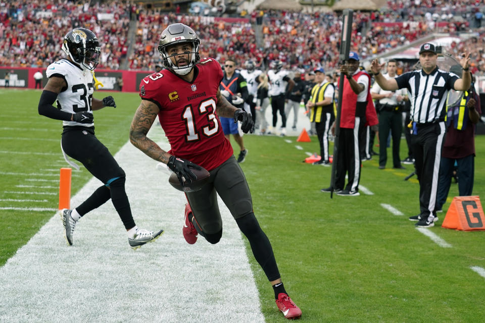 Tampa Bay Buccaneers wide receiver Mike Evans (13) runs for a touchdown past Jacksonville Jaguars cornerback Tyson Campbell (32) on a 3-yard pass play during the first half of an NFL football game Sunday, Dec. 24, 2023, in Tampa, Fla. (AP Photo/Chris O'Meara)