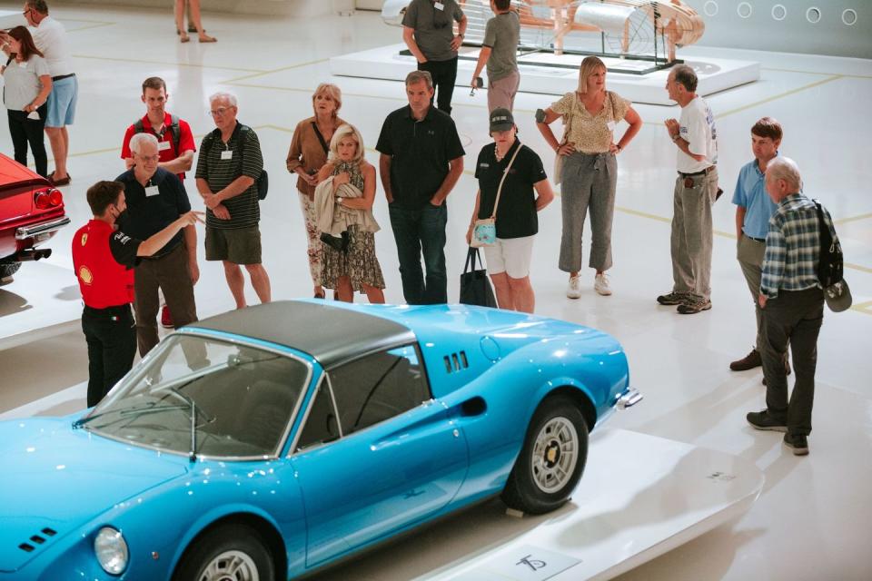 a group of people standing around a blue car