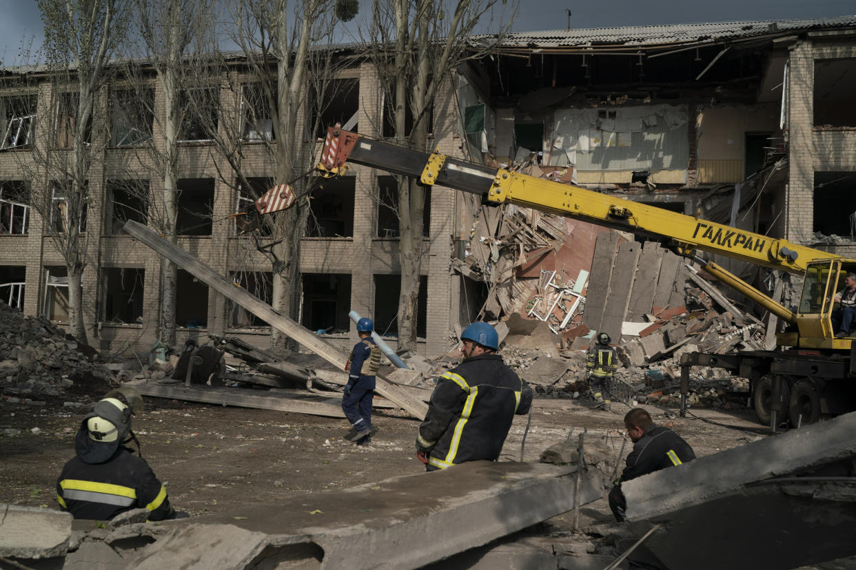 Rescue workers clear the debris at the scene where a woman was found dead after a Russian attack that heavily damaged a school in Mykolaivka, Ukraine, Wednesday, Sept. 28, 2022. (AP Photo/Leo Correa)