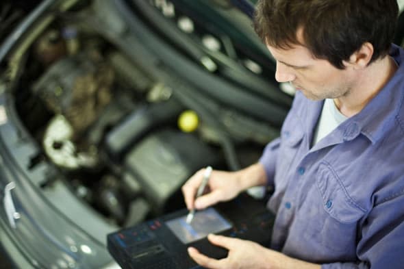 BM8XYM Mechanic using electronic tools to evaluate car performance