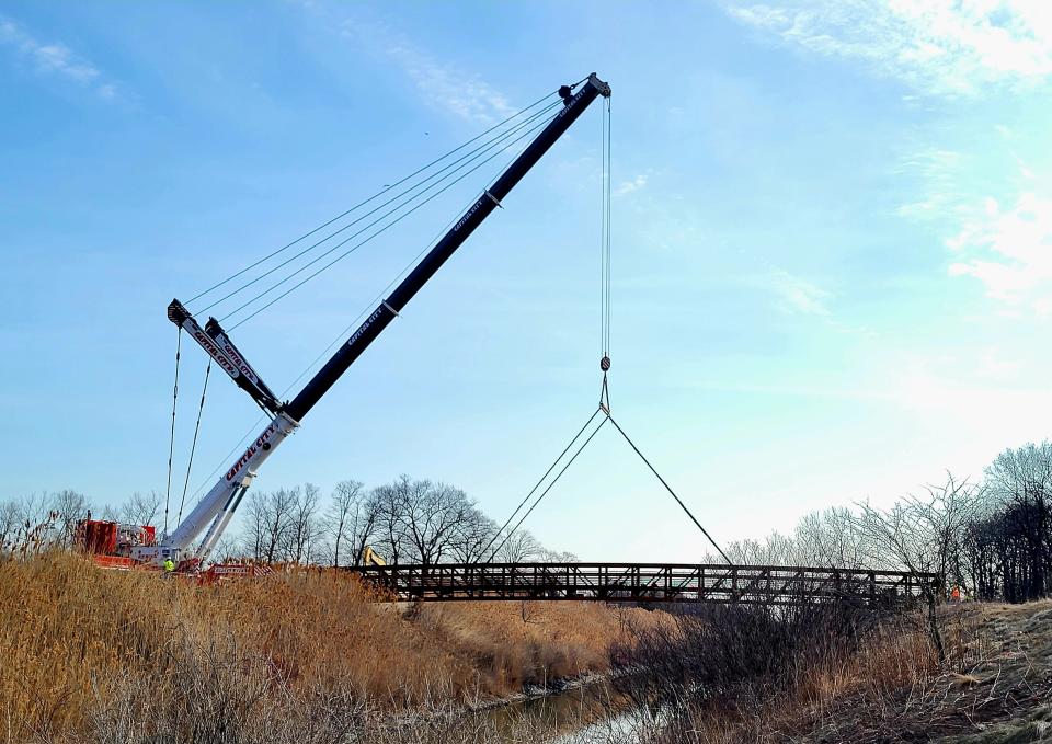 A 71,800-pound bridge is placed over the Black River Canal on Tuesday, March 21, 2023. According to Port Huron's department of public works, it took seven hours to assemble the crane used to move the bridge.