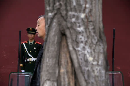 A man stands next to paramilitary police officers near Tiananmen Square on the first day of a plenary session of the 18th Central Committee of the Communist Party of China (CPC), in Beijing, China, October 24, 2016. REUTERS/Jason Lee