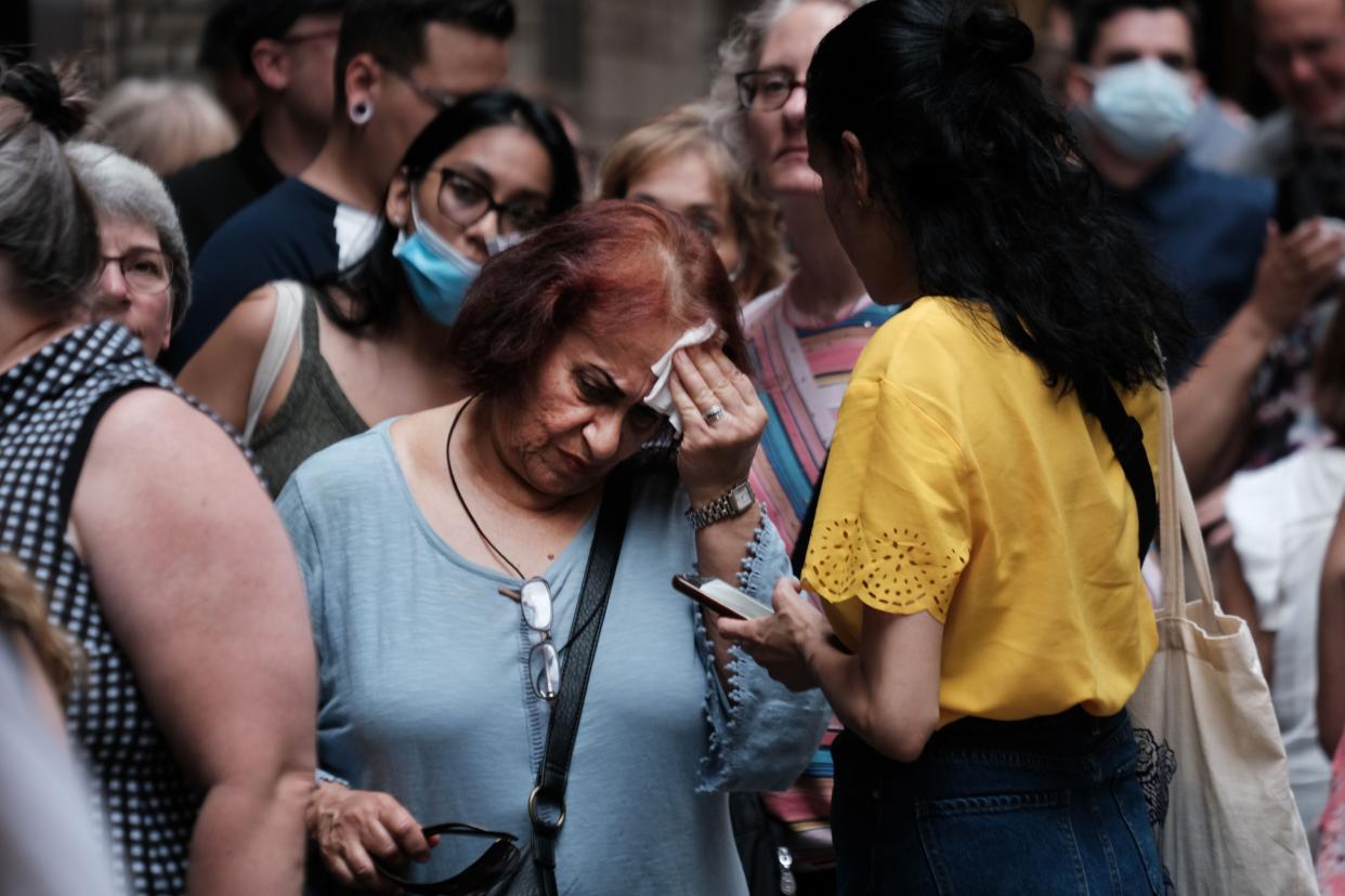 A woman wipes her brow as people wait in line to see Phantom of the Opera in midtown Manhattan as temperatures reach into the 90s on July 21, 2022 in New York City. 