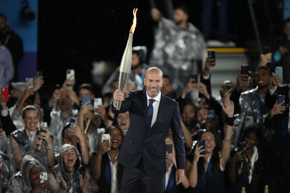 Zinedine Zidane carries the torch in Paris, France, during the opening ceremony of the 2024 Summer Olympics, Friday, July 26, 2024. (AP Photo/Natacha Pisarenko)