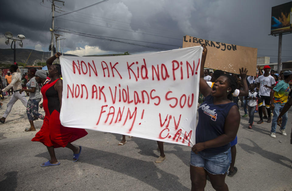 People protest carrying a banner with a message that reads in Creole: "No to kidnappings, no to violence against women ! Long live Christian Aid Ministries," demanding the release of kidnapped missionaries, in Titanyen, north of Port-au-Prince, Haiti, Tuesday, Oct. 19, 2021. A group of 17 U.S. missionaries including children was kidnapped by a gang in Haiti on Oct. 16. (AP Photo/Joseph Odelyn)