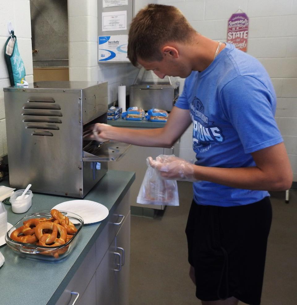 Alex Griffith pulls pretzels from a warmer at the concession stand at the Lake Park Aquatic Center. He's working as support staff this summer at the pool, feeling in where needed. He's saving money from his summer job to help with college this fall.