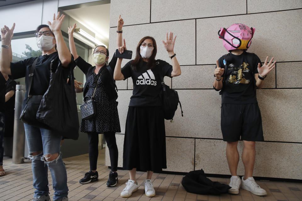 Protesters gesture with five fingers, signifying the "Five demands - not one less" outside a court during a protest in Hong Kong, Thursday, Aug. 27, 2020. Hong Kong police arrested 16 people, including two opposition lawmakers, on Wednesday on charges related to anti-government protests last year. (AP Photo/Kin Cheung)