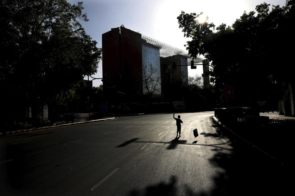 FILE- In this April 6, 2020 file photo, a homeless child tries to fly a kite on the middle of a deserted road during a nation wide 21 day lockdown amid concerns over the spread of new coronavirus, in New Delhi, India. India, a bustling country of 1.3 billion people, has slowed to an uncharacteristic crawl, transforming ordinary scenes of daily life into a surreal landscape. The country is now under what has been described as the world’s biggest lockdown, aimed at keeping the coronavirus from spreading and overwhelming the country’s enfeebled health care system. (AP Photo/Manish Swarup, File)