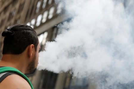 FILE PHOTO - A man uses a vape as he walks on Broadway in New York City