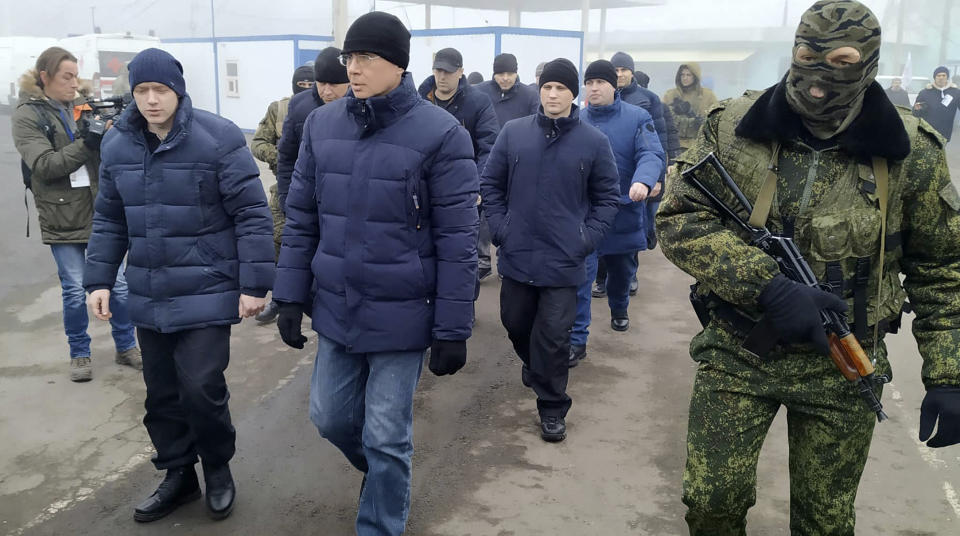 A Russia-backed separatist soldier escorts a group of separatists war prisoners after they were exchanged near the checkpoint Horlivka, eastern Ukraine, Sunday, Dec. 29, 2019. Ukrainian forces and Russia-backed rebels in the east have begun exchanging prisoners in a move aimed at ending their five-year-long war. (AP Photo/Alexei Alexandrov)