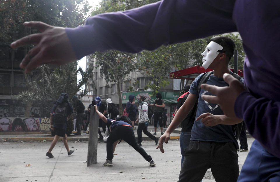 A mask demonstrator clash with the police during an anti-government protest in Santiago, Tuesday, Nov. 5, 2019. Chileans have been taking to the streets and clashing with the police to demand better social services and an end to economic inequality, even as the government announced that weeks of demonstrations are hurting the country's economic growth. (AP Photo/Esteban Felix)