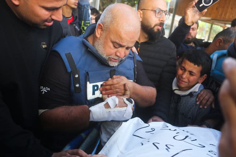 El periodista Wael Dahdouh, centro, de Al Jazeera, sostiene la mano de su hijo Hamza, que también trabajaba para Al Jazeera y quien murió en un ataque israelí en Rafah, en la Franja de Gaza, el domingo 7 de enero de 2024.