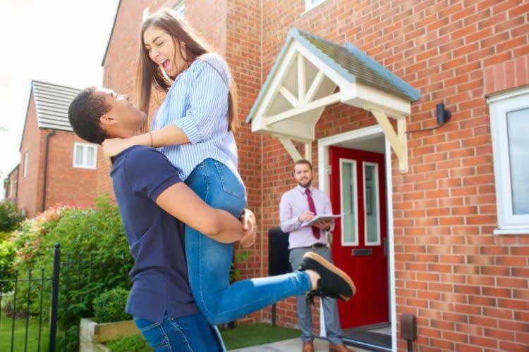 a couple embrace in front of their new home