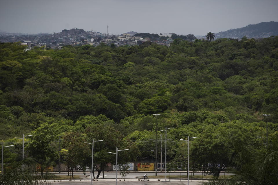 In this Nov. 7, 2019 photo, a man rides his bicycle past land that is part of a planned F1 racetrack in Rio de Janeiro, Brazil. The Company Rio Motorpark says it will pay up to $170 million to construct a track in the seaside city's impoverished Deodoro region. (AP Photo/Leo Correa)