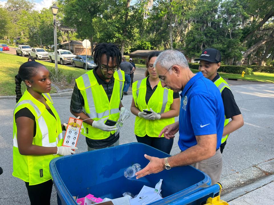 Jacksonville City Council member Ron Salem discusses the contents of his recycle bin with bin inspectors, (right to left) Jamal Simpson, Bertha Tate, Fredrick David and Elisah McDonald during the first stop of the "Feet on the Street" recycling initiative on May 12, 2023.