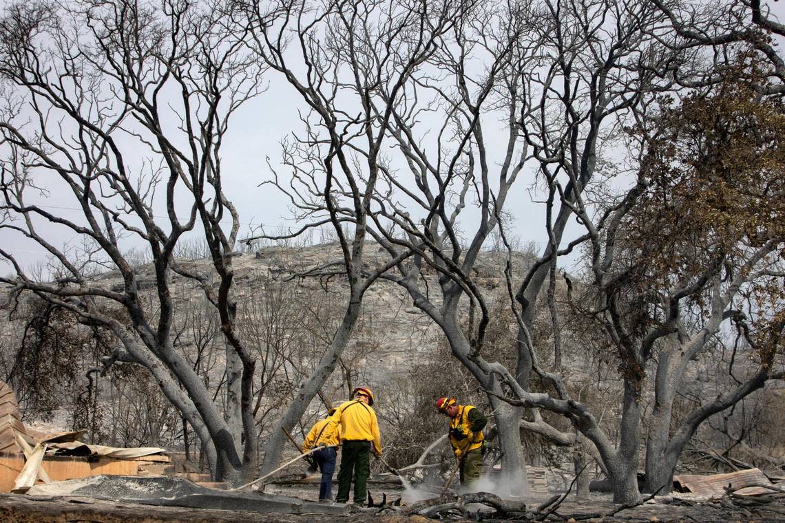 Firefighters soak the smoldering ground on the coast of Possum Kingdom Lake in Graford, Texas, on Wednesday, July 20, 2022.