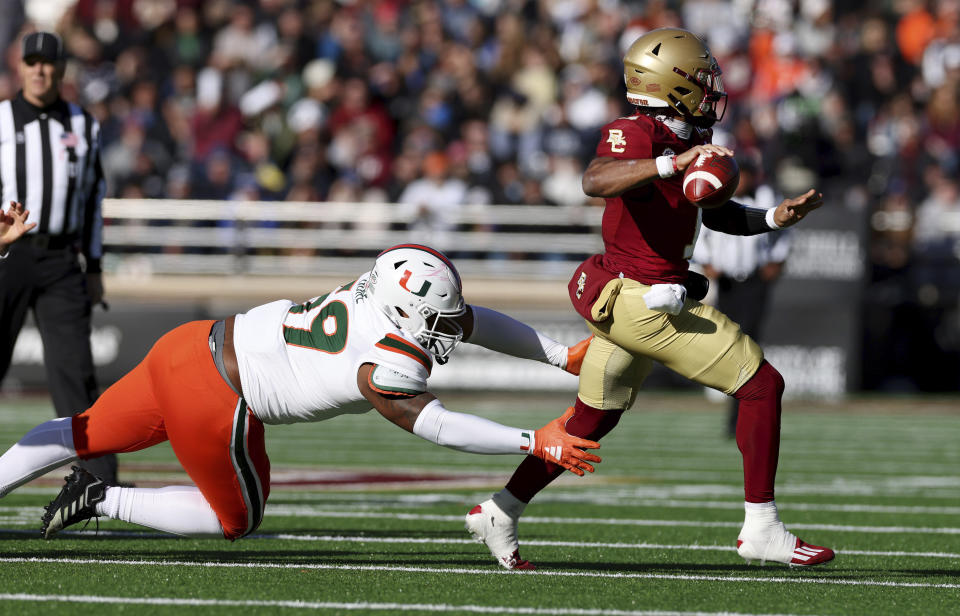 Miami defensive lineman Thomas Gore, left, chases Boston College quarterback Thomas Castellanos to the sideline during the first half of an NCAA college football game Friday, Nov. 24, 2023, in Boston. (AP Photo/Mark Stockwell)