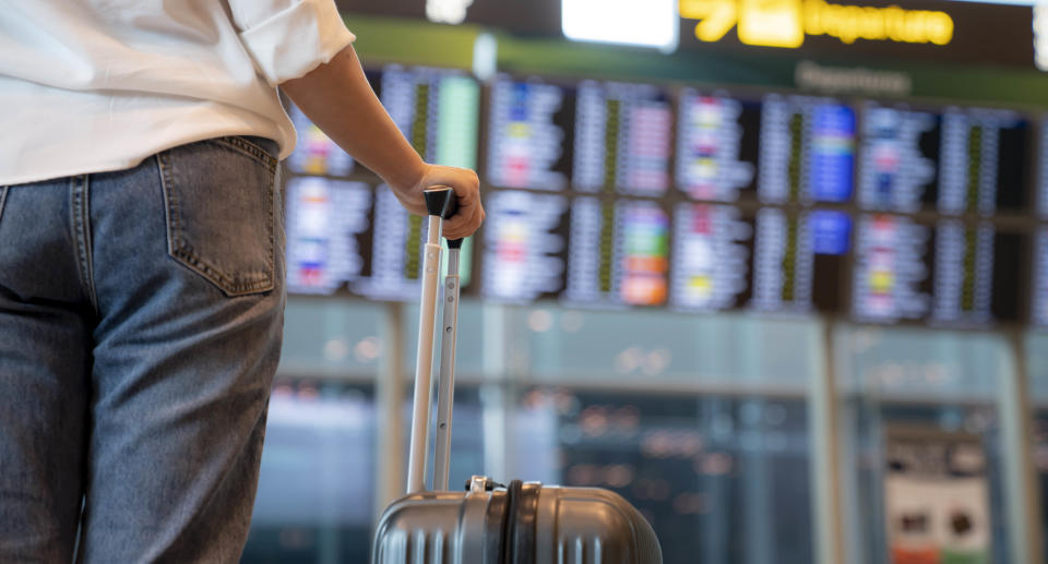 Female traveller standing in front of Flight display schedule in the International airport. Source: Getty Images