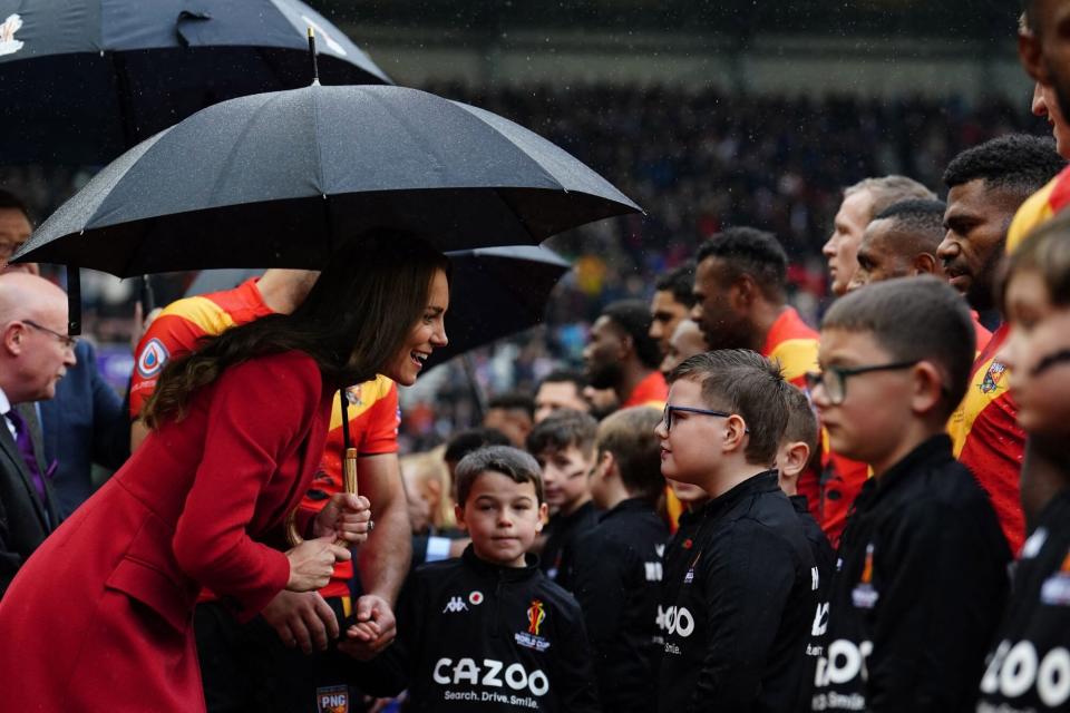 Britain's Catherine, Princess of Wales shelters from the rain under an umbrella as she meets the mascots before the 2021 rugby league World Cup men's Quarter Final match between England and Papua New Guinea at DW Stadium in Wigan in north-west England on November 5, 2022. (Photo by Martin Rickett / POOL / AFP) (Photo by MARTIN RICKETT/POOL/AFP via Getty Images)