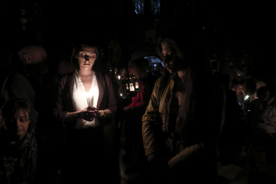 Orthodox faithful attend a mass after the "Holy Fire" brought from Jerusalem was delivered to worshippers, at a church in Athens, on Saturday, April 27, 2019. A lantern carrying a flame lit in Jerusalem's Holy Sepulcher Church was welcomed in Greece with honors reserved for visiting heads of state. But a senior cleric boycotted the ceremony, miffed that the "Holy Flame" did not land within his see.(AP Photo/Yorgos Karahalis)