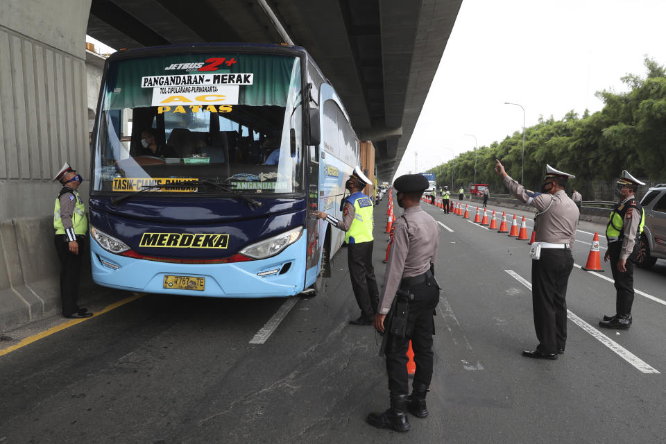 Indonesian police check bus passengers at a checkpoint during the imposition of large-scale restriction to curb the spread of the new coronavirus outbreak on toll road in Cikarang, West Java, Indonesia, Friday, April 24, 2020. Indonesia is suspending passenger flights and rail service as it restricts people in the world's most populous Muslim nation from traveling to their hometowns during the Islamic holy month of Ramadan because of the coronavirus outbreak. (AP Photo/Achmad Ibrahim)