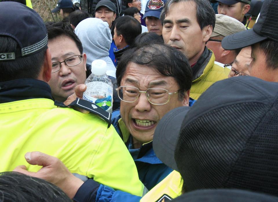 Parientes de los pasajeros desaparecidos en un transborddor hundido forcejean con policías mientras intentan llegar a la casa presidencial para protestar por las operaciones de rescate implementadas por el gobierno en un puerto en Jindo, Corea del Sur, el domingo 20 de abril de 2014. (Foto AP/Ahn Young-joon)