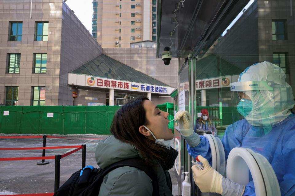 A health worker collects a swab sample on a journalist to test for COVID-19 at the parking lot of a hotel in Beijing on February 2, 2022, ahead of the Beijing 2022 Winter Olympic Games. (SEBASTIEN BOZON/AFP via Getty Images)