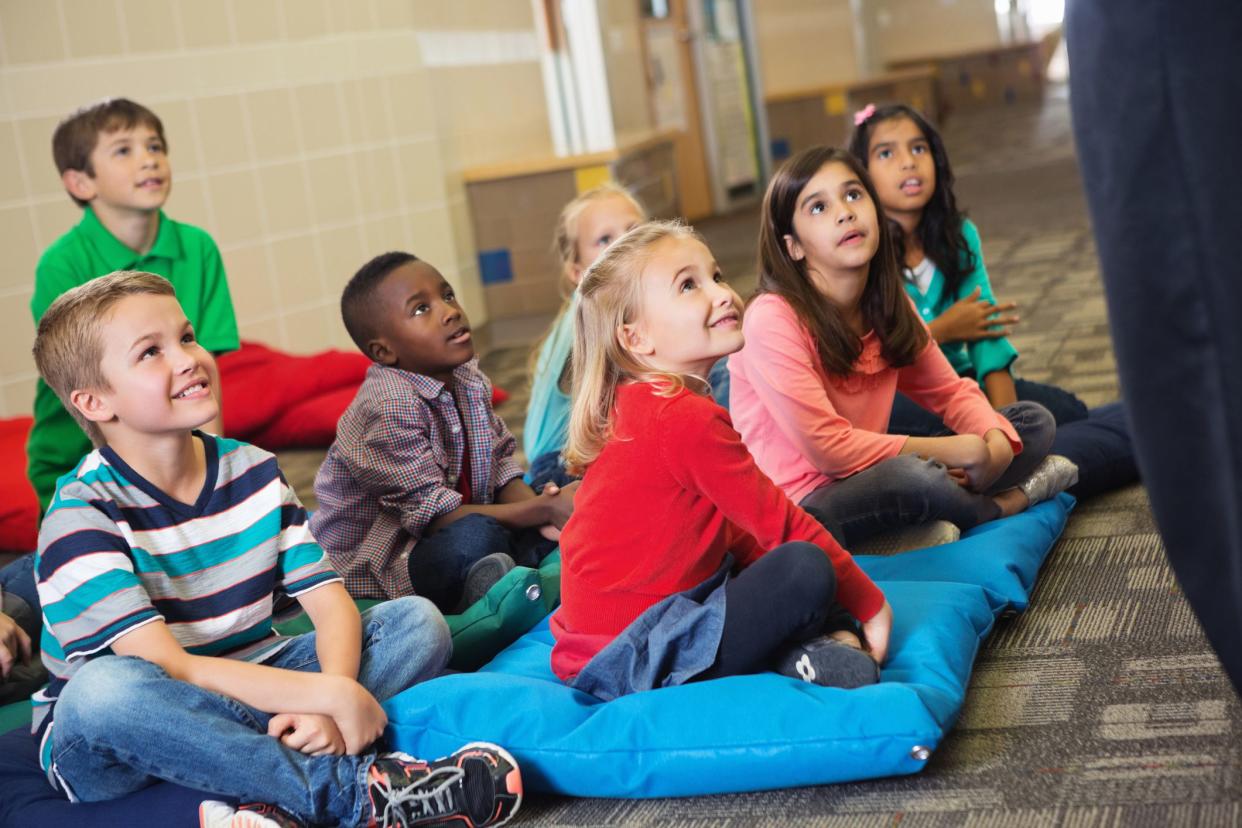 students on pillows listening to teacher