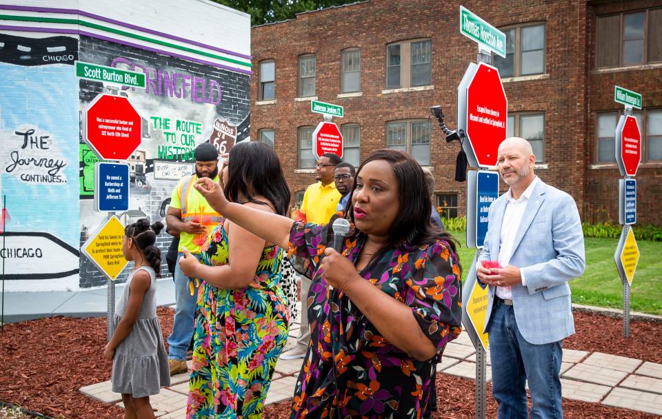 Gina Latham, center, describes the mural across the exterior wall of the Route History museum and visitors center after a ribbon-cutting ceremony in Springfield, Ill., on July 9. Next to the mural is a tribute to four important Black entrepreneurs in Springfield, two of whom were killed in a race riot in 1908. Route History highlights stories around the Black experience on historic Route 66.