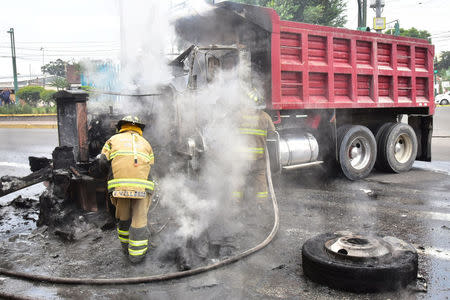 A firefighter extinguish fire on a truck used to block a road by gang members after a shootout between gang members and the Mexican army in Mexico City, Mexico July 20, 2017. REUTERS/Stringer