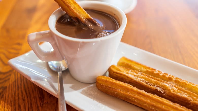 churros and chocolate dipping saucec on a whie plate