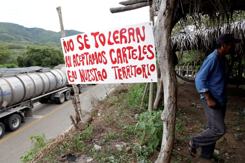 FILE PHOTO: A member of the Community Police is seen next to a sign reading "We don't tolerate nor accept drug cartels in our territory" at a checkpoint in the municipality of San Diego Xayakalan